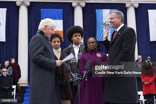 New York City Mayor Bill de Blasio, right, takes the oath of office administered by former U.S. President Bill Clinton, as his daughter, Chiara de...