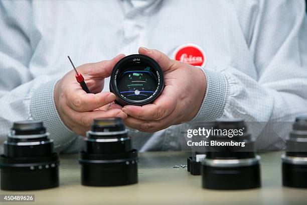 An employee holds a Noctilux 50mm 1:0.95 lens during manufacture inside the Leica Camera AG factory as the company celebrates their 100th...