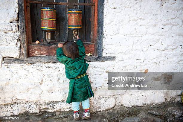 Young Bhutanese boy in traditional costume, the Gho, a knee-length robe somewhat resembling a kimono that is tied at the waist by a traditional belt...