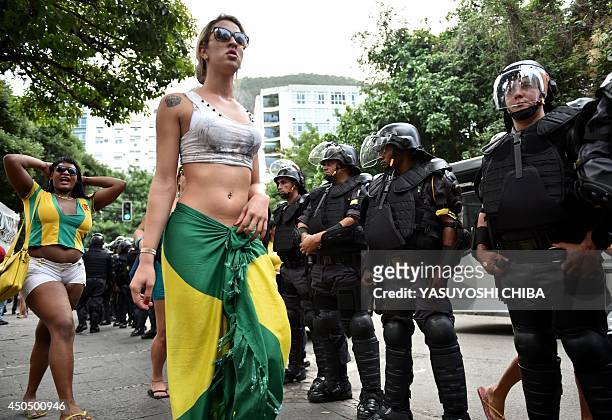 Fans of Brazil walk by riot policemen standing guard for the FIFA Fan Fest near Copacabana beach in Rio de Janeiro on June 12 just minutes before the...
