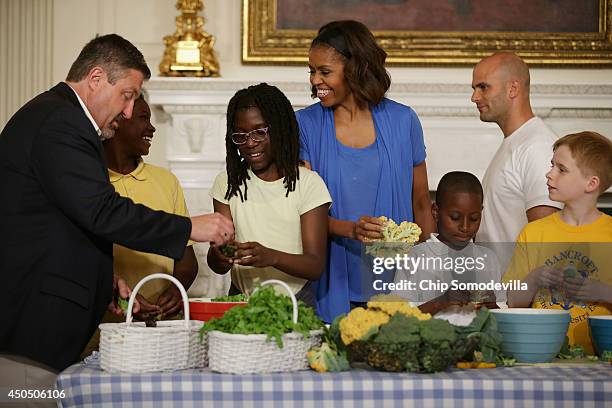 First lady Michelle Obama and West Virginia Department of Education Office of Child Nutrition Executive Director Richard Goff help students from five...