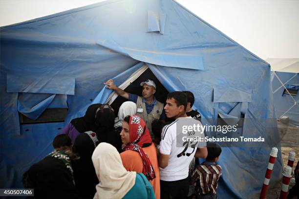 Iraqi refugees gather food and blankets in a makeshift camp at a Kurdish checkpoint in Kalak after fleeing from the city of Mosul which has been...