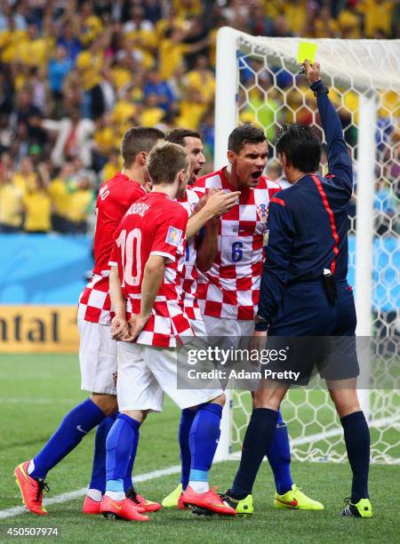 Referee Yuichi Nishimura shows Dejan Lovren of Croatia a yellow card in the second half during the 2014 FIFA World Cup Brazil Group A match between...