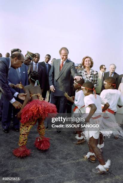 Juan Carlos of Spain and Queen Sofia of Spain are greeted on December 4, 1995 by traditional dancers in the Ivorian capital Yamoussoukro where the...