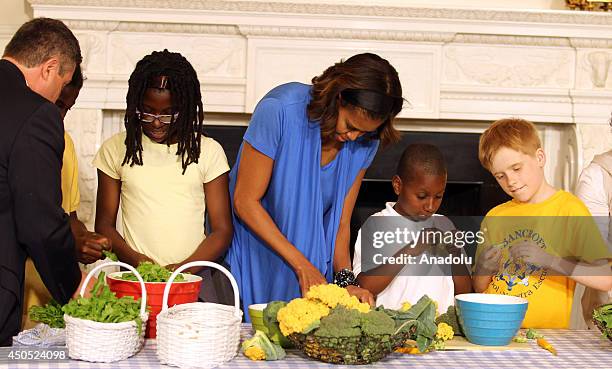 First lady Michelle Obama helps students from five District of Columbia schools to make food using the summer crop from the White House Kitchen...