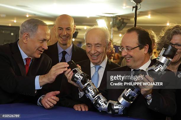 French President Francois Hollande shares a light moment with his Israeli counterpart Shimon Peres and Prime Minister Benjamin Netanyahu as he holds...