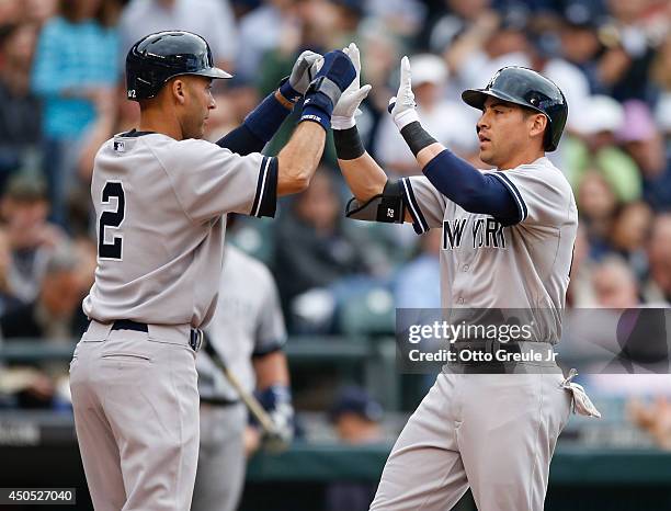 Jacoby Ellsbury of the New York Yankees is congratulated by Derek Jeter after hitting a two-run home run in the first inning against the Seattle...