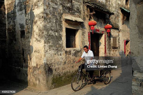 Villager rides a tricycle down an old street on June 12, 2014 at the ancient Hongcun Village, China. Hongcun Village, located in the eastern province...