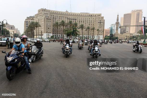 Egyptian bikers ride their motorcycles past the landmark Mogamaa government building in Cairo's Tahrir Square, where protesters had battled police...