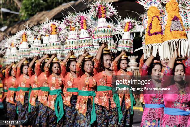 Participants wearing traditional costumes carry offerings on their heads during the opening of the 36th Bali International Arts Festival on June 13,...