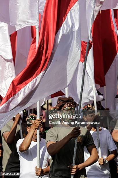 Participants from Indonesian Army hold Indonesia flags wearing traditional costumes carry offerings on their head during the opening of the 36th Bali...