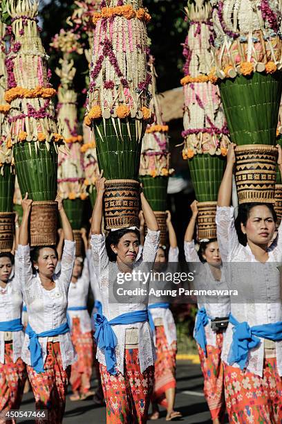 Participants wearing traditional costumes carry offerings on their head during the opening of the 36th Bali International Arts Festival on June 13,...