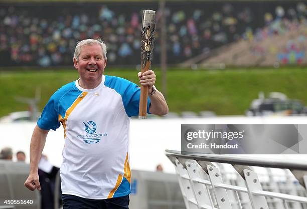 In this handout image provided by Glasgow 2014 Ltd, Baton bearer Brendan Foster carries the Queen's Baton over the Tyne Bridge on June 13, 2014 in...