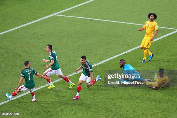 Oribe Peralta of Mexico celebrates his goal with teammates Miguel Layun and Hector Herrera as goalkeeper Charles Itandje of Cameroon looks on in the...