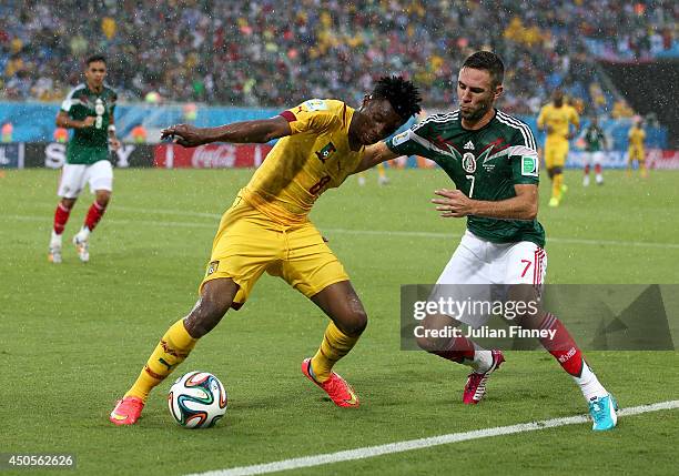 Benjamin Moukandjo of Cameroon holds off a challenge by Miguel Layun of Mexico during the 2014 FIFA World Cup Brazil Group A match between Mexico and...