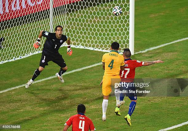 Tim Cahill of Australia goes up for a header against Gary Medel of Chile and scores a goal past goalkeeper Claudio Bravo during the 2014 FIFA World...