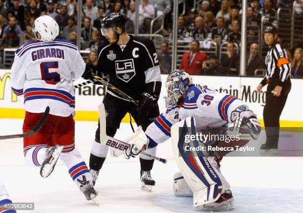 Dan Girardi of the New York Rangers get a stick in the face from Dustin Brown of the Los Angeles Kings as goaltender Henrik Lundqvist defends the net...
