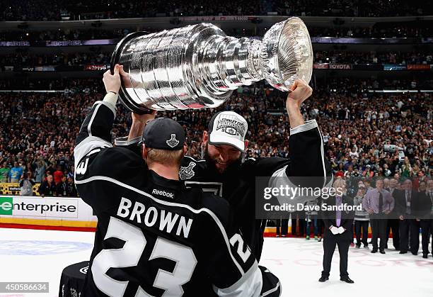 Dustin Brown of the Los Angeles Kings passes the Stanley Cup to teammate Robyn Regehr after their team 3-2 in double overtime over the New York...