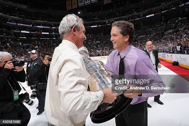 Darryl Sutter of the Los Angeles Kings hands the Stanley Cup Trophy over to general manager Dean Lombardi after defeating the New York Rangers in the...
