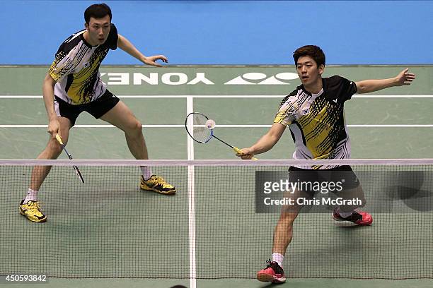 Yong Dae Lee of Korea returns a shot as team mate Yeon Seong Yoo watches on during their Men's Doubles semi final match against Angga Pratama and...