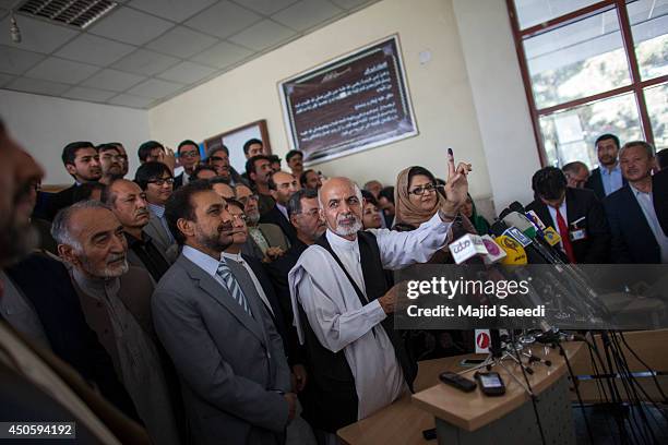 Afghan presidential candidate Ashraf Ghani holds up his inked finger as he speaks to media after casting his vote at a polling station on June 14,...