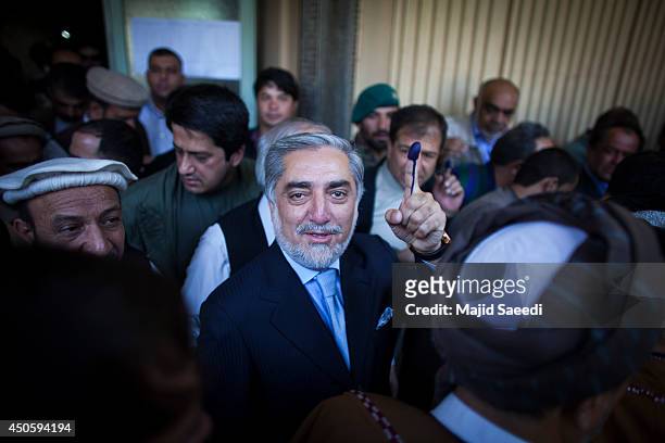 Afghan presidential candidate Abdullah Abdullah holds up his inked finger as he speaks to media after casting his vote at a polling station on June...