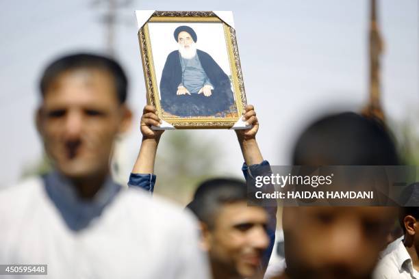 An Iraqi man holds up a portrait of Shiite cleric Grand Ayatollah Ali al-Sistani during a demonstration in the central Shiite Muslim shrine city of...