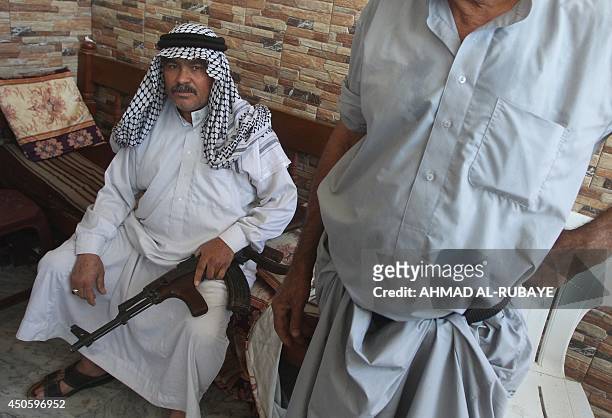 An Iraqi Shiite man holds his weapon as he sits at a recruitment centre in the Iraqi town of Jdaideh in the Diyala province on June 14 following the...