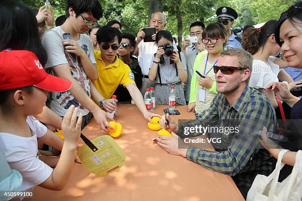 Dutch conceptual artist Florentijn Hofman signs for fans as he attends a charitable donation ceremony for autistic children at Hangzhou Xixi National...