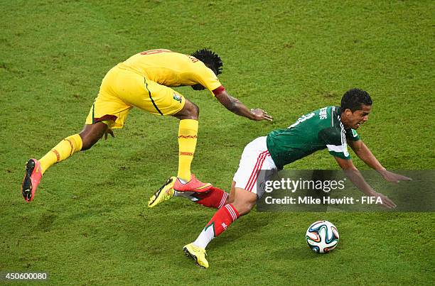 Giovani dos Santos of Mexico goes to ground after a challenge by Benjamin Moukandjo of Cameroon during the 2014 FIFA World Cup Brazil Group A match...