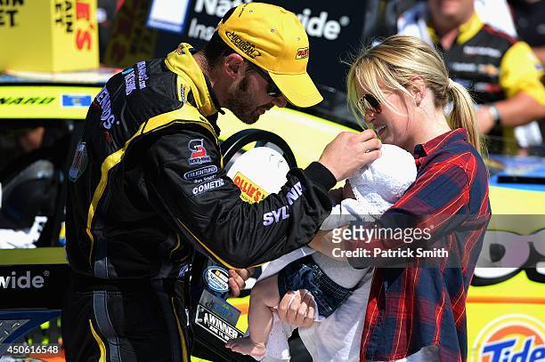 Paul Menard, driver of the Nibco/Menards Chevrolet, left, celebrates in victory lane with wife Jennifer and daughter Remi after winning the NASCAR...