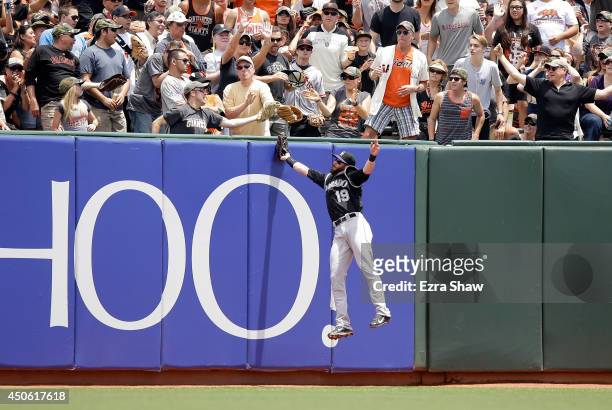 Fan catches a home run ball hit by Hunter Pence of the San Francisco Giants as Charlie Blackmon of the Colorado Rockies leaps into the air to try to...
