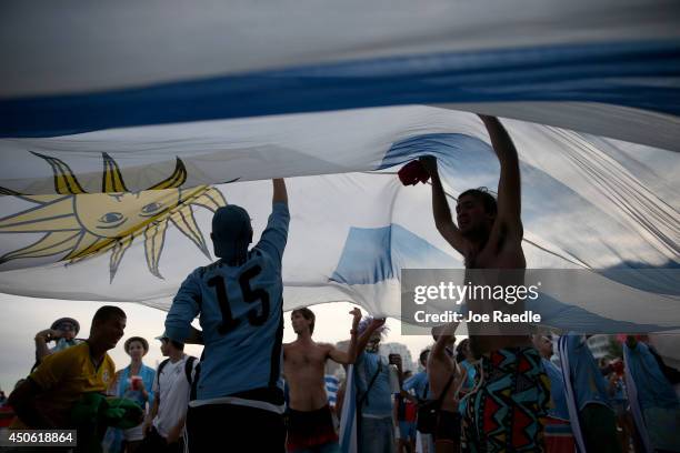 Uruguay soccer team fans dance under their countries flag as their team play against Costa Rica while watching the game on the giant screen showing...