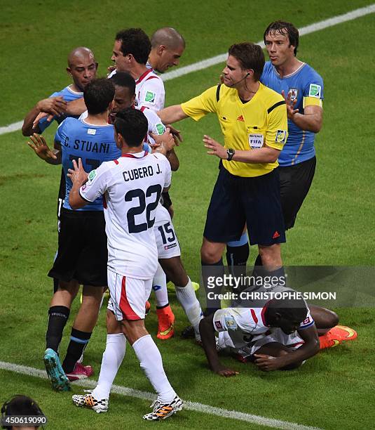 German referee Felix Brych breaks up an altercation between Uruguay and Costa Rica players after Costa Rica's forward Joel Campbell was brought to...
