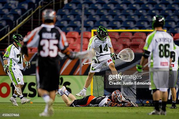 Curtis Dickson of the Denver Outlaws scores a diving goal during the third quarter as Drew Adams of the New York Lizards jumps above him during the...