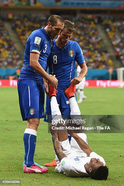 Giorgio Chiellini and Claudio Marchisio of Italy help Raheem Sterling of England stretch during the 2014 FIFA World Cup Brazil Group D match between...