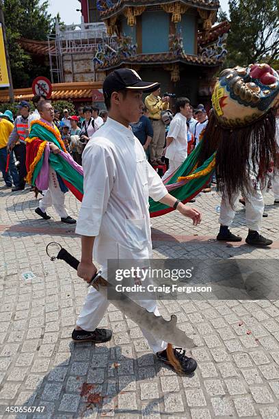 Young man carries a blade weapon during a ceremony to mark the birthday of the Bao Sheng Emperor on the 14th day of the 3rd lunar month in the...