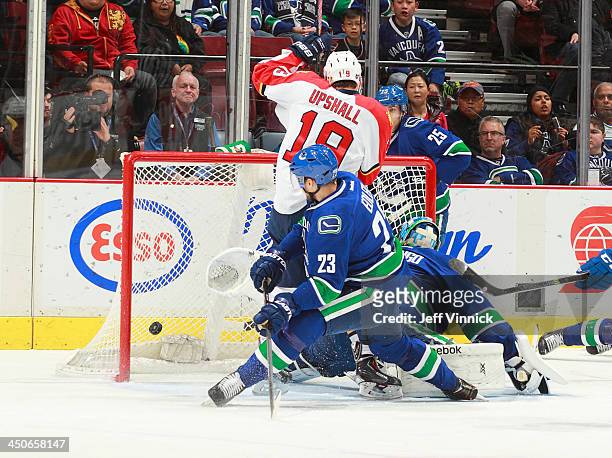 Scottie Upshall of the Florida Panthers and Alexander Edler of the Vancouver Canucks watch the puck enter the goal behind Roberto Luongo of the...