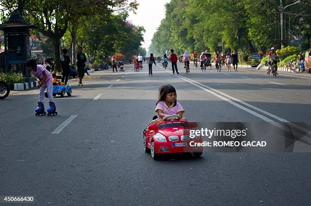 Child rides an electric toy car in Solo city's main avenue on June 15, 2014 during the car-free Sunday morning in the central Java island city....