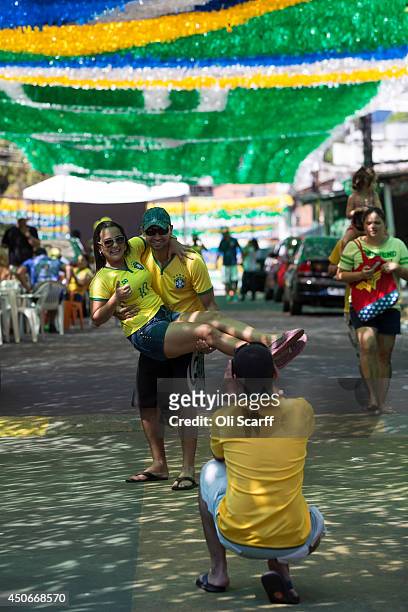 Football fans pose for a photograph on Rua Santa Isabel which is covered with colourful streamers to celebrate the FIFA World Cup on June 15, 2014 in...