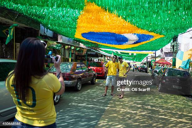 Football fans pose for a photograph on Rua Santa Isabel which is covered with colourful streamers to celebrate the FIFA World Cup on June 15, 2014 in...