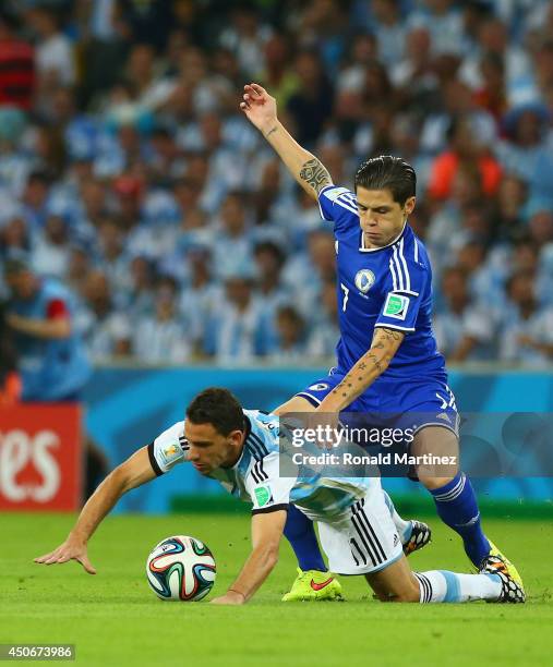 Muhamed Besic of Bosnia and Herzegovina challenges Maxi Rodriguez of Argentina during the 2014 FIFA World Cup Brazil Group F match between Argentina...