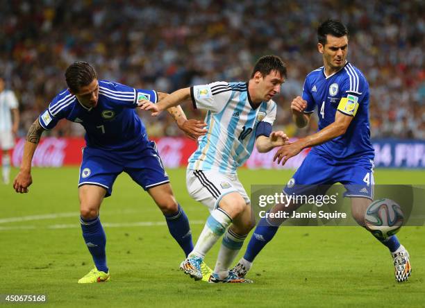 Lionel Messi of Argentina controls the ball against Muhamed Besic and Emir Spahic of Bosnia and Herzegovina during the 2014 FIFA World Cup Brazil...