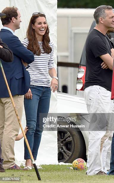 Catherine, Duchess of Cambridge watches Prince William, Duke of Cambridge and Prince Harry play in a charity polo match as baby Prince George clings...