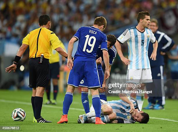 Lionel Messi of Argentina lies on the field as Edin Visca of Bosnia and Herzegovina stands over him after a foul during the 2014 FIFA World Cup...