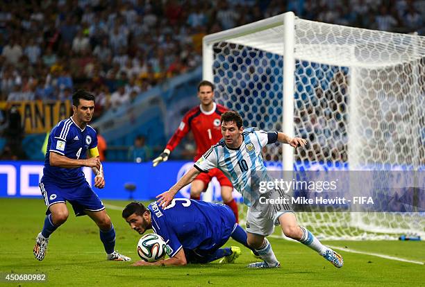 Lionel Messi of Argentina competes for the ball with Emir Spahic and Vedad Ibisevic of Bosnia and Herzegovina during the 2014 FIFA World Cup Brazil...