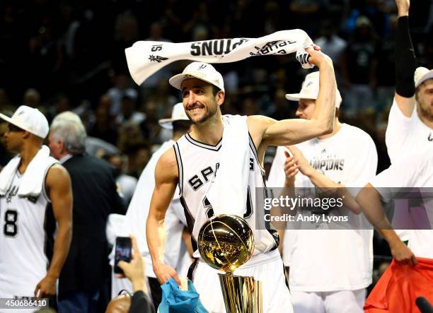 Manu Ginobili of the San Antonio Spurs celebrates with the Larry O'Brien trophy after defeating the Miami Heat in Game Five of the 2014 NBA Finals at...