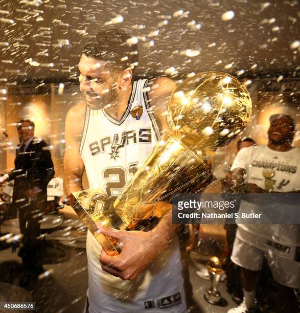 Tim Duncan of the San Antonio Spurs showered with champagne in the locker room with the Larry O'Brien Trophy after winning the 2014 NBA Finals at...