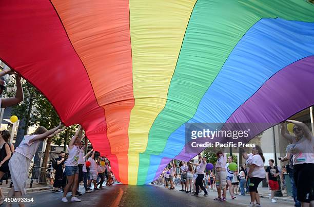 Gay Pride volunteers wave a giant rainbow colored flag as a world symbol for the LGBT community and their rights. Hundreds of people on Saturday...