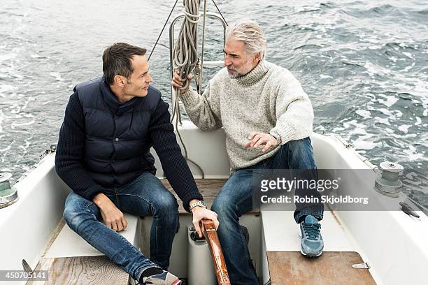 two mature men talking in sailingboat - sailingboat stock-fotos und bilder